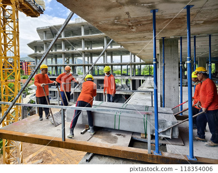 Workers at a building under construction take slabs from a crane Workers at a building under construction take slabs from a crane 118354006