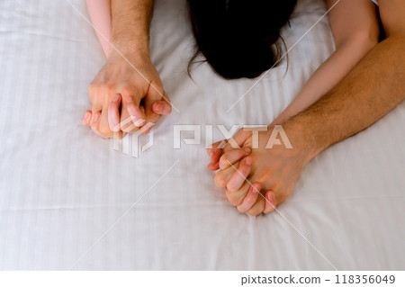Man is stroking woman's hands lying in bed making love, hands close-up. 118356049