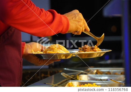 A close-up of a hand scooping curry onto a plate A close-up of a hand scooping curry onto a plate 118356768