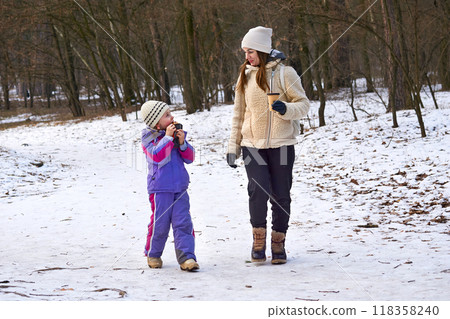 Mother and child daughter walk in a winter forest park 118358240