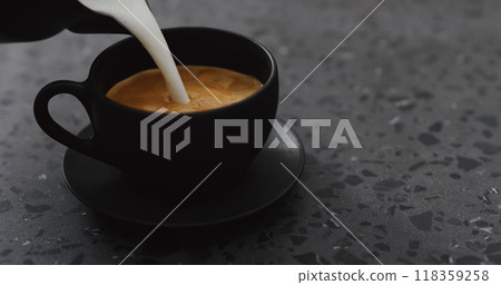 pouring steamed milk into cappuccino in black cup on terrazzo countertop pouring steamed milk into cappuccino in black cup on terrazzo countertop 118359258