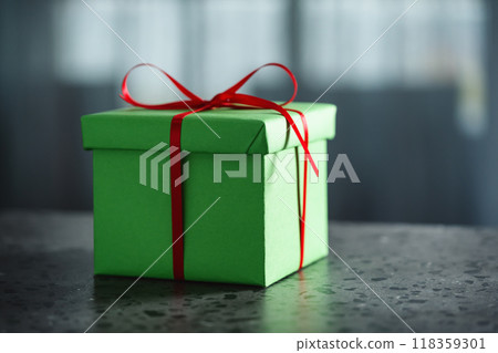 Green gift box with red ribbon against window on terrazo countertop with copy space Green gift box with red ribbon against window on terrazo countertop with copy space 118359301