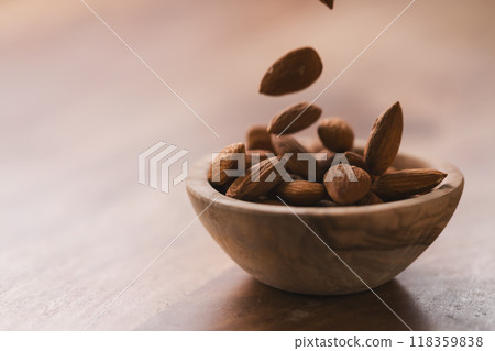 peeled almonds falling in wood bowl with copy space peeled almonds falling in wood bowl with copy space 118359838