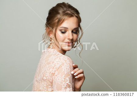 Cute glam woman fashion model with makeup and updo hairstyle on gray studio background Cute glam woman fashion model with makeup and updo hairstyle on gray studio background 118360817