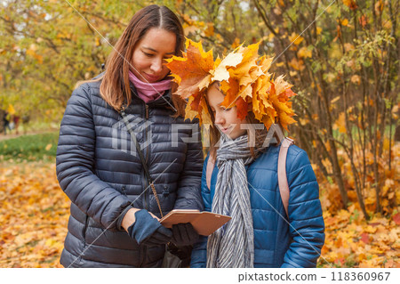 Portrait of mother and daughter holding smartphone in autumn park background 118360967