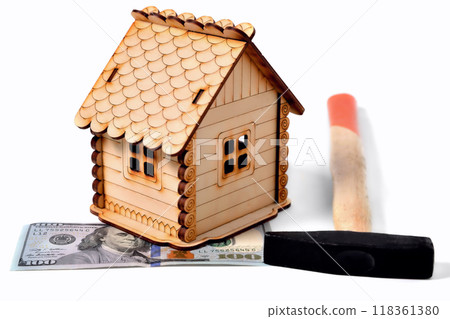 Wooden toy house, a banknote of 100 dollars and a hammer on a white background, isolate Wooden toy house, a banknote of 100 dollars and a hammer on a white background, isolate 118361380