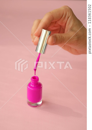 pink nail polish with bottle and brush on pink background, top view. woman paints her nails pink nail polish with bottle and brush on pink background, top view. woman paints her nails 118361502