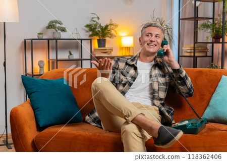 Man making retro telephone from 90s conversation call with friends sitting on couch at home room 118362406