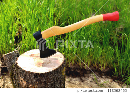 a beautiful-shaped ax sticks out in a tree, with a yellow handle close-up, on a natural background 118362463