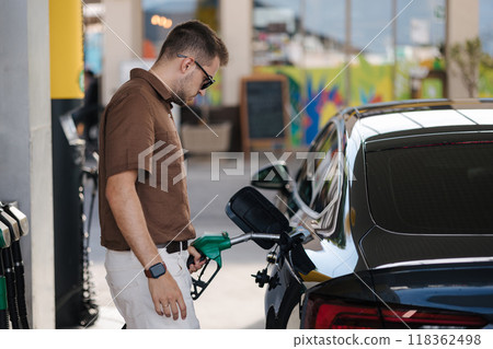 Handsome man start refueling car at self service gas station. Petrol concept. Gasoline. Fuel price increase 118362498