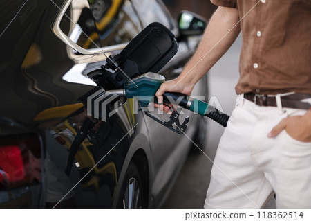 Close-up of human hand pumping gasoline car with fuel at the refuel station. Driver refueling the car at a gas station. Benzine. Fuel price increase Close-up of human hand pumping gasoline car with fuel at the refuel station. Driver refueling the car at a gas station. Benzine. Fuel price increase 118362514