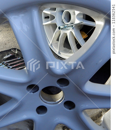 View of the process of repairing an automobile wheel through the spokes of a dismantled rim 118362541