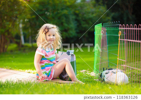 Kids feed rabbit in sunny garden Kids feed rabbit in sunny garden 118363126