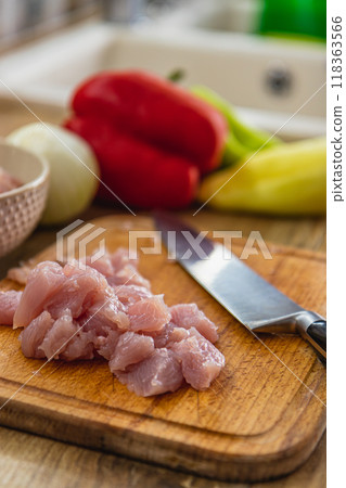 Pieces of chicken fillet on a cutting board, whole vegetables on the side Pieces of chicken fillet on a cutting board, whole vegetables on the side 118363566