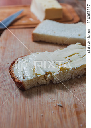Close-up of a buttered slice of homemade bread with butter in the background Close-up of a buttered slice of homemade bread with butter in the background 118363587
