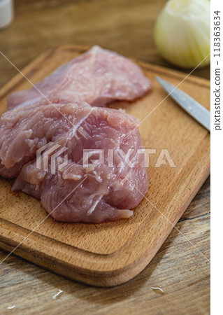 Chicken breast on a cutting board, onions on the side 118363634