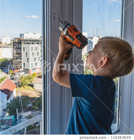 The child helps to fasten the lock with a screwdriver 118363639