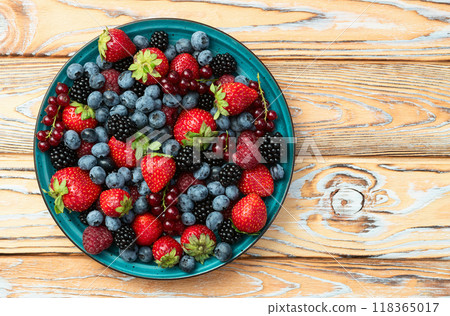 Mix of ripe colorful berries in bowl photography . Blueberry , strawberry , raspberry , blackberry and red currant . Top view 118365017