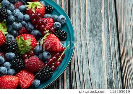 Mix of ripe colorful berries in bowl photography . Blueberry , strawberry , raspberry , blackberry and red currant . Top view 118365019