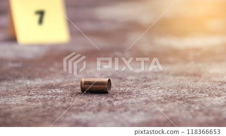 Spent bullet casing lying on the ground with blur number 7 sign. Concepts of shooting sports and security highlighting the dual nature of firearms in both competitive sport and protective measures. 118366653