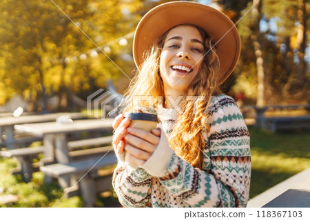 Fall concept woman drinking coffee on bench against backdrop of lake. Enjoying, solitude with nature 118367103