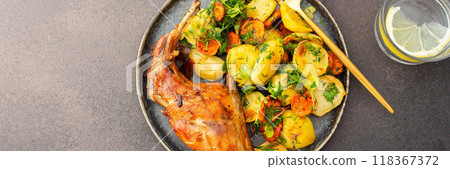 Baked rabbit with potatoes and carrots, a set table with food, a glass of wine and a vase of flowers Baked rabbit with potatoes and carrots, a set table with food, a glass of wine and a vase of flowers 118367372