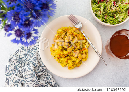 Stewed rice with chicken breast and mixed salad with radishes and various seeds, a served table with food and a vase of flowers 118367392