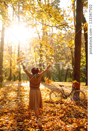 Beautiful Woman throws up autumn leaves and having fun in autumn park. Relaxation, enjoying. 118367502