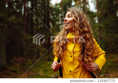 Traveler woman in yellow coat explores, walks through wild forest in nature. Vacation travel concept Traveler woman in yellow coat explores, walks through wild forest in nature. Vacation travel concept 118367773
