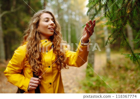 Traveler woman in yellow coat explores, walks through wild forest in nature. Vacation travel concept Traveler woman in yellow coat explores, walks through wild forest in nature. Vacation travel concept 118367774