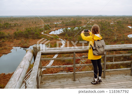 Young woman looks at amazing nature on observation deck. Tourist enjoys a view of magical swamps. Young woman looks at amazing nature on observation deck. Tourist enjoys a view of magical swamps. 118367792