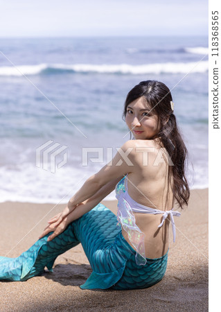 年輕的女美人魚坐在夏日海邊的沙灘上微笑 118368565
