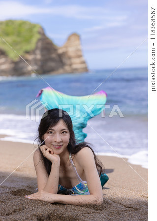 年輕的女美人魚坐在夏日海邊的沙灘上微笑 118368567