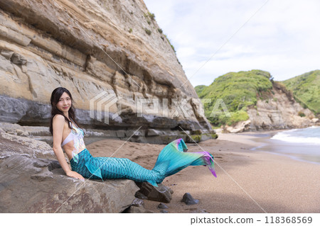 坐在海邊懸崖前的沙岩上的年輕女美人魚 118368569