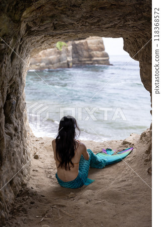 年輕的女美人魚坐在俯瞰大海的洞穴裡 118368572