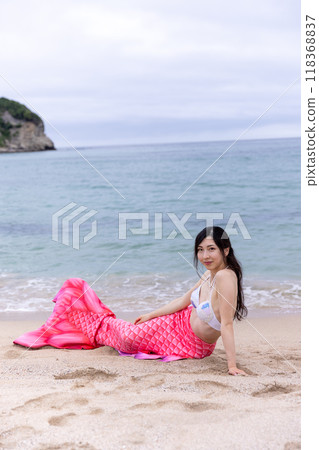 Young female mermaid lying on the sandy beach of the sea 118368837