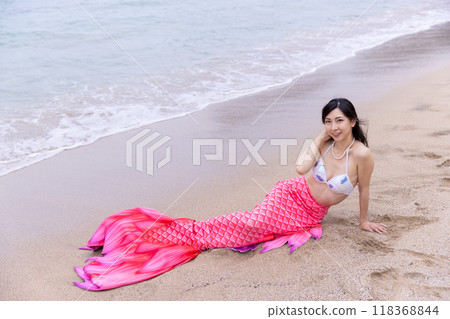 年輕的女美人魚躺在海邊的沙灘上 118368844
