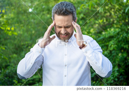 Stressed businessman suffering from migraine attack natural background, headache 118369216