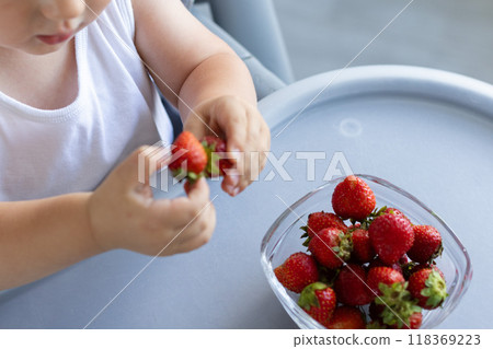 Little child taking strawberry from the plate. Little child taking strawberry from the plate. 118369223