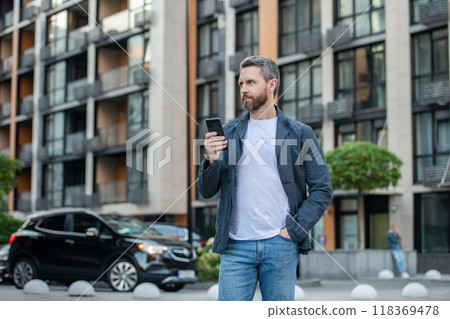 man chatting on phone in the street. man chatting on phone outside. 118369478