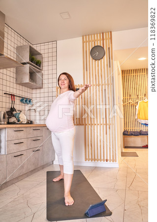 Pregnant woman practicing yoga poses in kitchen for relaxation and mindfulness Pregnant woman practicing yoga poses in kitchen for relaxation and mindfulness 118369822