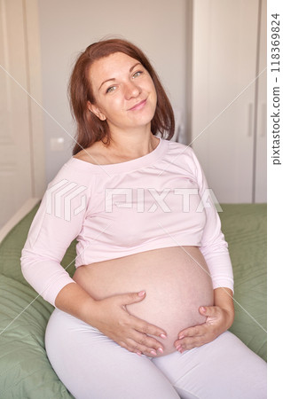 Joyful expectant mother relaxing at home in comfortable maternity wear Joyful expectant mother relaxing at home in comfortable maternity wear 118369824