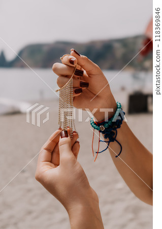 Hands Jewelry Beach - Woman holding silver chain necklace on beach. Hands Jewelry Beach - Woman holding silver chain necklace on beach. 118369846