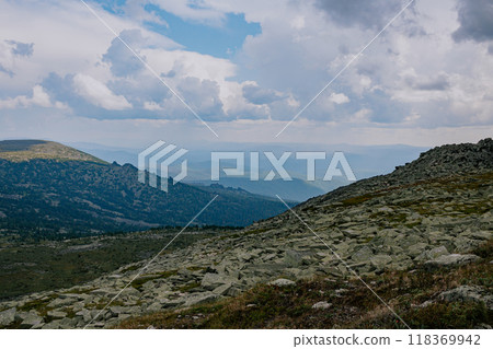 Rocky hills stretching far beyond the horizon and curly clouds. Summer natural landscape in forest-tundra Rocky hills stretching far beyond the horizon and curly clouds. Summer natural landscape in forest-tundra 118369942