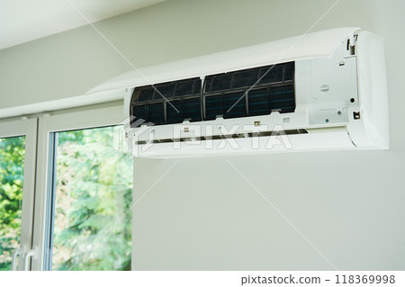 White air conditioner unit is mounted on wall, ready for maintenance. Climate system with opened front cover revealing internal components. Repairing HVAC in apartment White air conditioner unit is mounted on wall, ready for maintenance. Climate system with opened front cover revealing internal components. Repairing HVAC in apartment 118369998