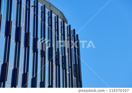 Close-up of modern glass building facade with geometric patterns reflecting sky. Contemporary architectural design. 118370107
