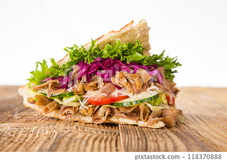 Doner Kebab Doner Kebap fast food snack in flatbread on a wooden table Doner Kebab Doner Kebap fast food snack in flatbread on a wooden table 118370888