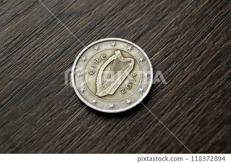 Irish 2 euro coin. Used coin on a dark wooden table. 118372894
