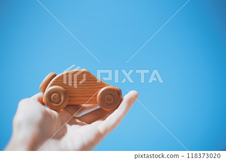 Man's hand holding wooden car and blue sky background Man's hand holding wooden car and blue sky background 118373020