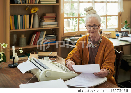 Senior Woman Reviewing Documents in Cozy Home Office 118373486